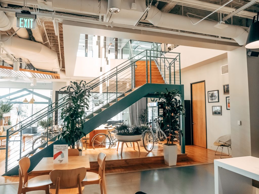Bright modern open office with bicycles, expansive staircase, and plants offering a welcoming workspace environment.